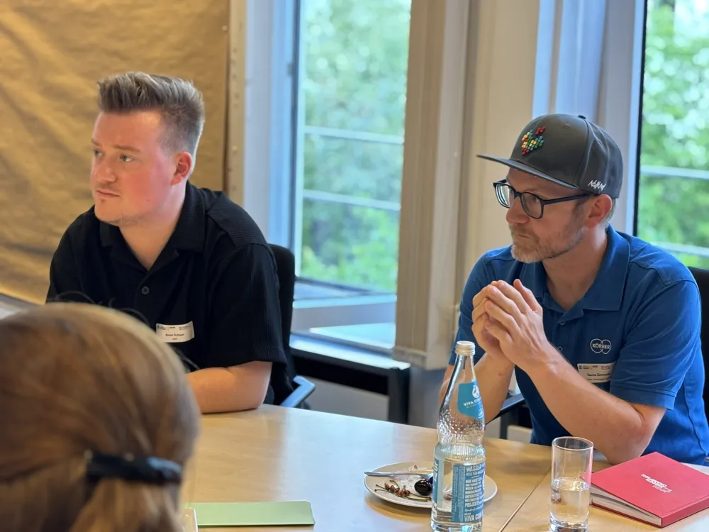 Foto von zwei Teilnehmenden am Tisch.