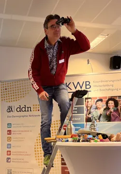 Ein Teilnehmer steht auf der Leiter und schaut durch ein Fernglas